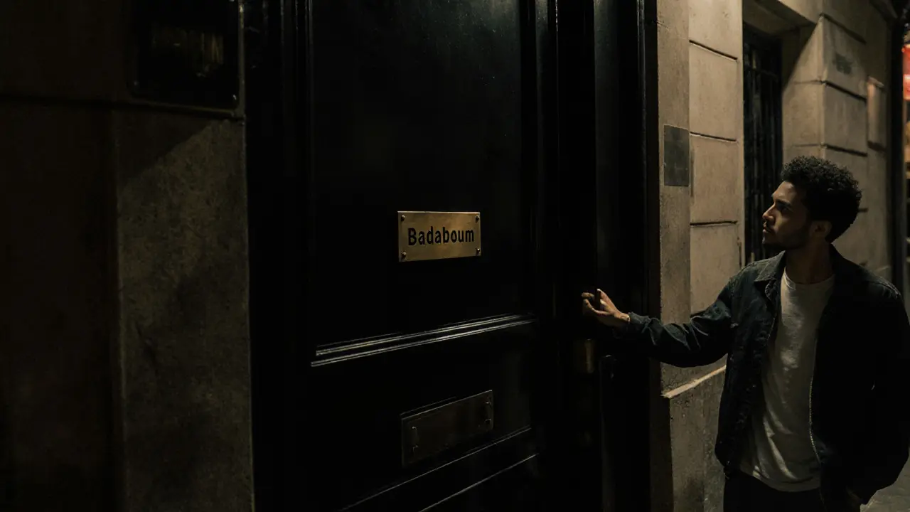 Unmarked black door on a quiet Paris street with a small brass plaque reading &#039;Badaboum&#039; in the night.